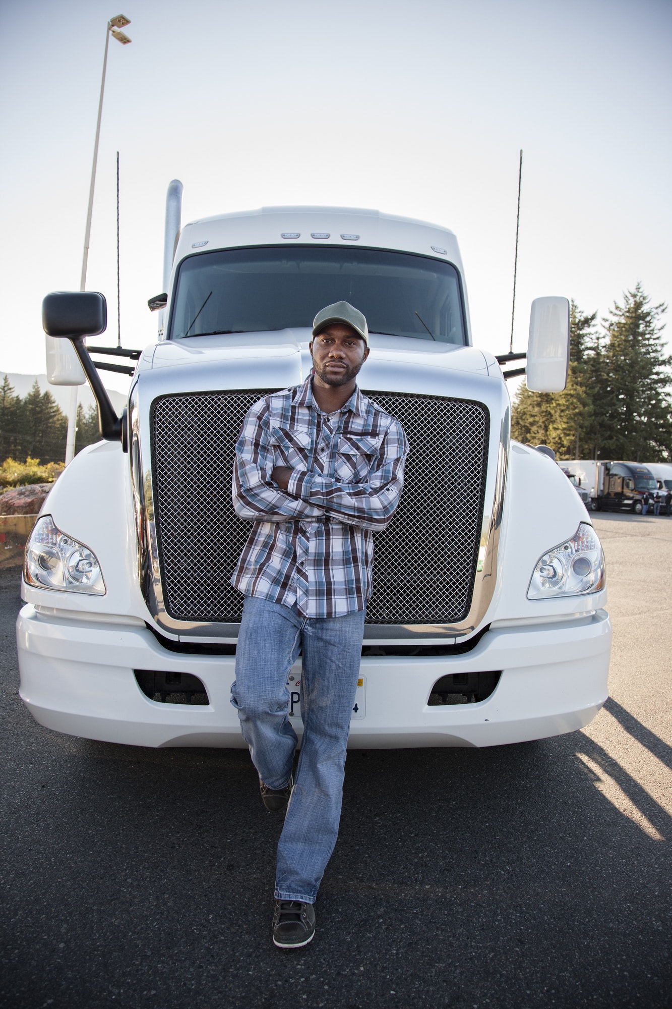 Black man truck driver near his truck parked in a parking lot at a truck stop